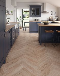 a kitchen with wooden flooring and blue cabinets in the center, along with two bar stools