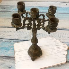 a small metal candelabra with five candles on it sitting on a wooden table