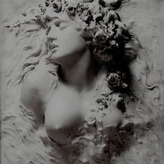 a black and white photo of a woman's head with flowers in her hair