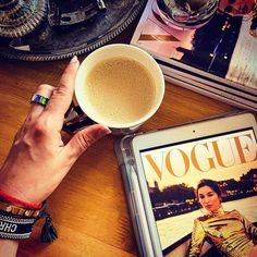 a person's hand holding a cup of coffee next to a magazine on a table