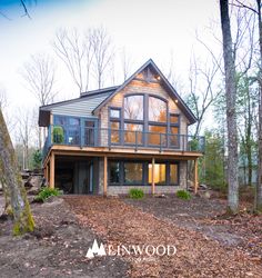 a large house in the woods with lots of trees and leaves on the ground around it