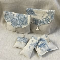 three blue and white linen bags sitting on top of a bed