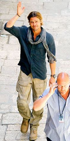 two men walking down the street with one holding his hand up