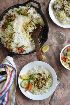 rice and vegetables in a skillet on a wooden table with two plates of food