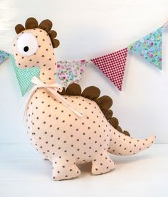 a stuffed toy dinosaur sitting on top of a white table next to bunting flags