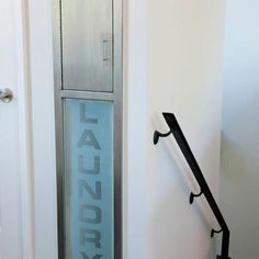 an open door with the word laundry on it in front of a white wall and black handrails