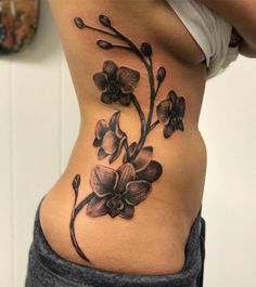 a woman's lower back tattoo with flowers on her stomach and the bottom part of her body