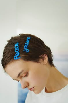 a young man is looking down at his cell phone and has two hair clips on his head