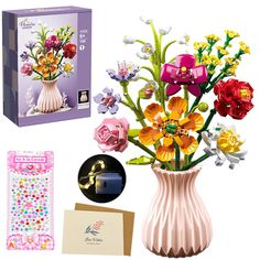 a vase filled with lots of colorful flowers next to a card and notepad on top of a table