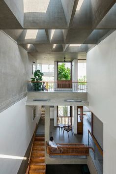 a person sitting on a bench in the middle of a room with stairs and windows