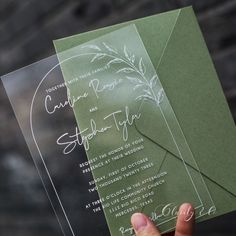 a person holding up a green and white wedding card with the wording on it