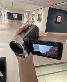 a person holding up a camera in an art gallery