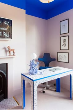 a blue and white living room with a table, chair, fireplace and pictures on the wall