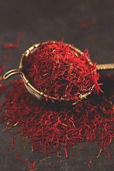 a bowl filled with red saffron seeds on top of a table