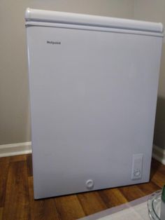 a white refrigerator sitting on top of a hard wood floor