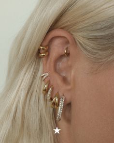 a woman with blonde hair wearing gold ear cuffs and an earring made out of metal