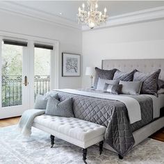 a bedroom with a large bed, chandelier and two doors leading to the outside