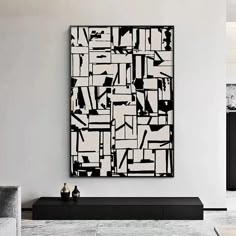 a black and white abstract painting hangs on the wall in a modern living room area