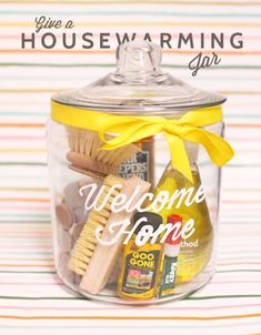 a glass jar filled with cleaning supplies on top of a striped table cloth and the words welcome home above it