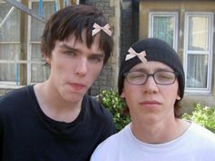 two young men standing next to each other in front of a house