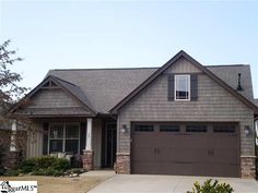 a brown house with two garage doors and windows