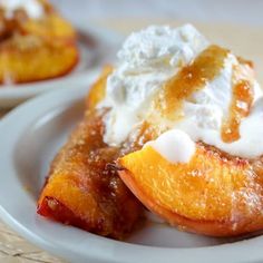 two white plates topped with peaches covered in whipped cream and fruit on top of each other