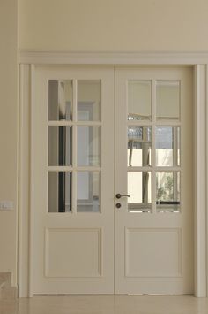 a white double door with glass panels on the side and an entry way leading to another room