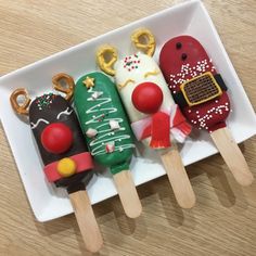 three popsicles decorated with christmas decorations on a white plate next to pretzels