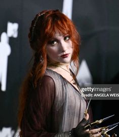 a woman with red hair holding scissors in her hand