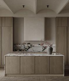 a large kitchen with marble counter tops and wooden cabinetry, along with two vases on the island