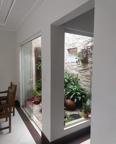 an open door leading to a patio with potted plants on the outside and inside