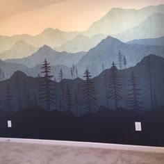 there is a large mural on the wall in this room that has mountains and trees painted on it