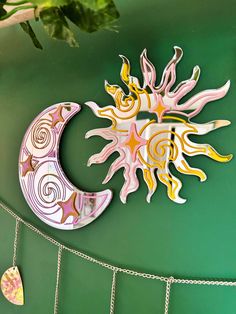 a metal sun and moon hanging on a green wall