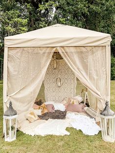 an outdoor tent set up with pillows and lanterns