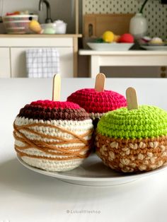 two crocheted apples sitting on top of a white plate next to each other