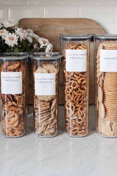 three clear containers filled with cookies and crackers next to a vase full of flowers