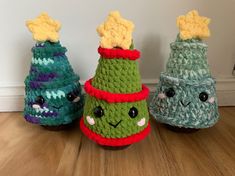 three crocheted christmas trees sitting on top of a wooden floor next to each other