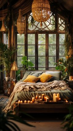 a bed with lots of candles on it in front of a window filled with potted plants