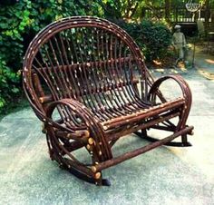 a wooden rocking chair sitting on top of a cement floor next to bushes and trees