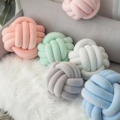 four different colored pillows sitting on top of a white fur covered floor next to a gray couch