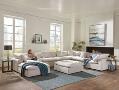 two people sitting on couches in a living room with hardwood floors and white walls