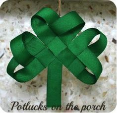 a green ribbon hanging from a hook on a marble wall with a knot in the shape of a four - leaf clover