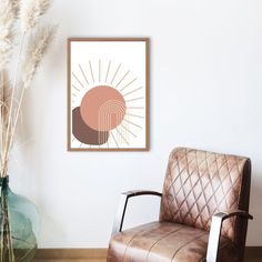 a brown leather chair sitting next to a vase with dried grass in front of it