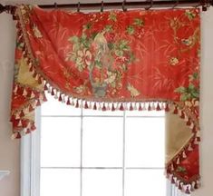 the window is decorated with red flowers and tassels on it's valance