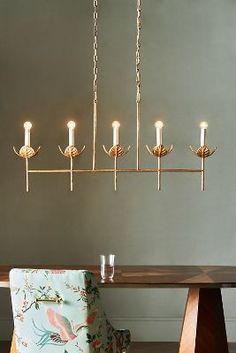 a chandelier hanging over a dining room table with two chairs and a blue chair