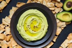 an avocado dip in a black bowl surrounded by crackers