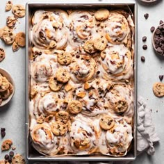 a pan filled with cookies and frosting on top of a table next to chocolate chips