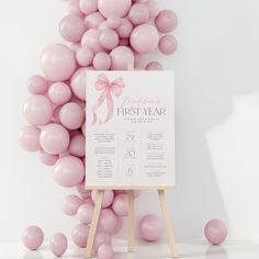 a sign that is next to some pink balloons in the shape of a dress on a wooden easer