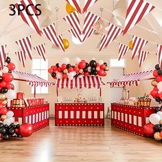 a room filled with red, white and black balloons on top of wooden flooring