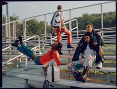 three young people sitting on bleachers with their feet in the air and one person standing up